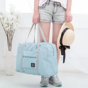 Details of the light blue travel duffel bag showing durable fabric handles and front pocket.