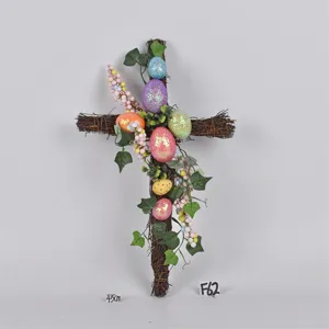 Easter cross twig wreath detail with glitter colorful eggs, green leaves and berries decoration.