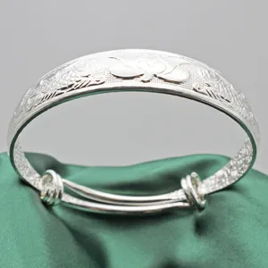 Dettaglio di bracciale rigido etnico in argento vintage con incisione a loto su seta verde