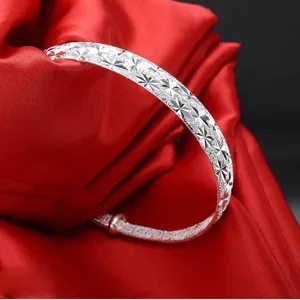 Dettaglio di bracciale rigido retrò placcato argento con incisione a stella su seta rossa