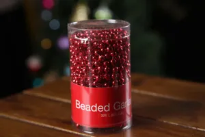 Red plastic Christmas beaded garland in clear storage container, 32ft holiday decoration.