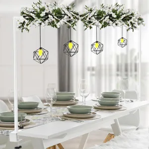 Soporte de arco colgante para mesa con guirnalda de flores blancas y lámpara geométrica.