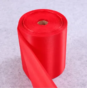 Close-up detail shot of bright red satin fabric roll, ideal for festive decoration and crafts.