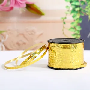 Close-up shot of shiny gold laser ribbon on a black spool, perfect for balloon decoration.