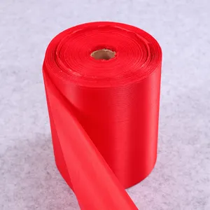 Bright red satin fabric roll for festive decorations, ceremonies, and traditional events.