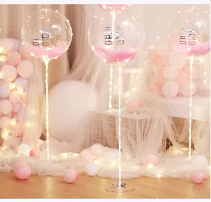 Details of LED bobo balloon table stand set with feathers and warm lights for party setup scene.