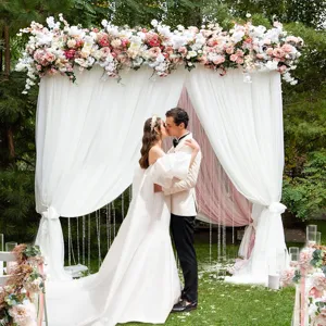 Support de fond d'arche de mariage avec rideaux blancs et décor floral pour cérémonie.