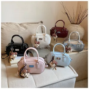 Detailed view of fashionable solid color bowling shoulder bags with cute bear pendants and metal badge.