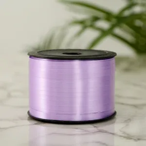 Close-up detail view of light purple plastic ribbon roll on marble surface, smooth texture.