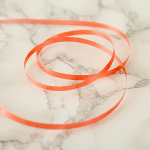 Close-up of bright orange balloon ribbon, smooth plastic material for gift wrapping and decor.