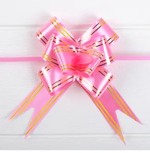 Detalle del lazo rosa brillante con rayas doradas para decoración de paquetes de regalo.