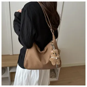 Vue détaillée du sac bandoulière hobo kaki décontracté avec joli pendentif en peluche.