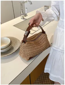 Sac a main en paille tressee avec poignee en cuir marron et serrure pour femme elegante.