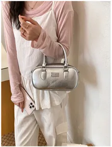 Detailed shot of a silver metallic bowling handbag, featuring a retro solid color and chic design.