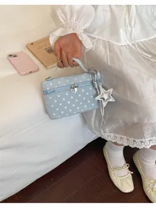 Detailed shot of light blue polka dot vanity bag with star pendant, lifestyle scene.