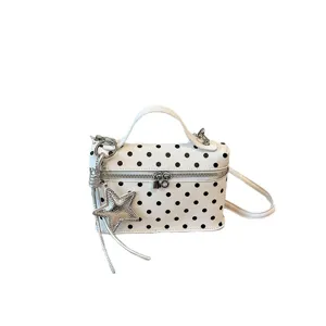 White polka dot shoulder handbag with top handle and stylish star charm accessory.