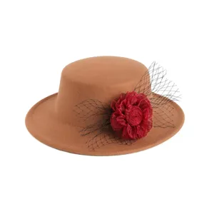 Detailansicht eines klassischen braunen Filzhuts mit roter Stoffblume und schwarzem Netzschleier