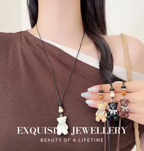 Primo piano del dettaglio della collana con ciondolo orsetto smaltato con perle e cordino.