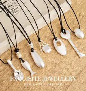 Collana con ciondolo argento opaco minimalista su corda di pelle nera, maglione lungo.