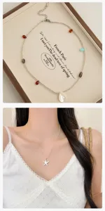 Gros plan sur le collier superposé avec pendentifs étoile de mer et coquillage, perles.
