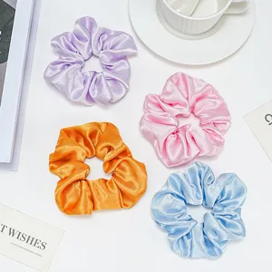 Vue détaillée de quatre chouchous en satin colorés en violet, rose, orange et bleu pastel
