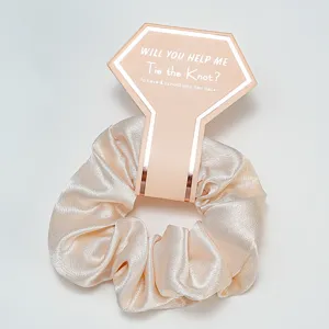 Vue détaillée d'un chouchou en satin champagne avec une carte en papier diamant