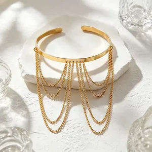 Dettaglio bracciale da braccio a catena con nappine multistrato dorato, stile punk elegante.