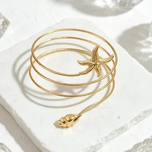 Detalle hermoso del brazalete dorado con estrella de mar y concha para el verano.
