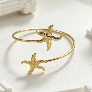 Detalle de pulsera rígida de estrella de mar dorada, joyería de metal estilo playa de verano.