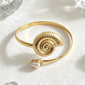 Prachtige gouden schelp open armmanchet armband detailshot met delicate parel accentuering.