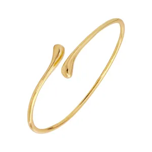 Primer plano de una elegante pulsera rígida dorada con extremos en lágrima y un acabado brillante.