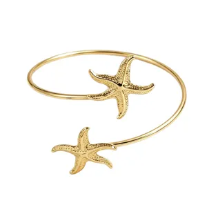 Brazalete abierto dorado con doble diseño de estrella de mar texturizada, ideal para la playa.