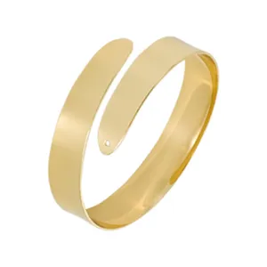 Dettaglio bracciale rigido aperto in metallo dorato, superficie geometrica liscia.