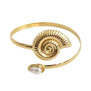 Gouden open armband met prachtig schelpdesign en parelaccent voor de ultieme strandlook.