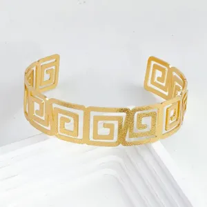 Bracelets manchette ouverts dores avec motif geometrique grec ajoure pour les femmes.