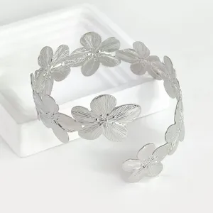 Detalle brazalete brazo flor metal plateado, joya verano playa ajustable elegante.