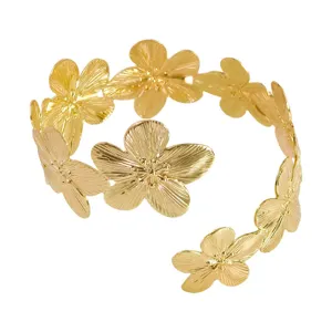 Primer plano detalle del brazalete de metal dorado con flores, abierto ajustable.