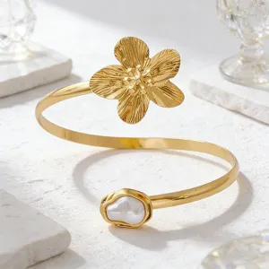 Elegantes goldenes Armreif-Detail mit strukturierter Blume und Perle als Akzent.