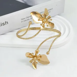 Detalle de brazalete de flor de metal dorado, pulsera abierta ajustable, brillo metálico elegante.