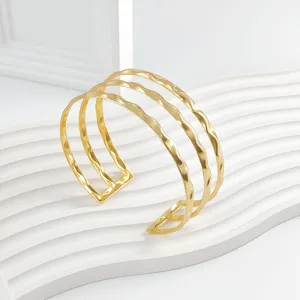 Brazalete abierto ondulado de tres capas de metal dorado, detalle de joyería de moda.