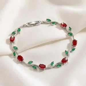 Detailed close-up of a stylish silver-tone branch bracelet featuring sparkling red and green zircon stones.