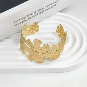 Close-up of gold metal open cuff bracelet featuring hollow floral daisy design for stylish wear.