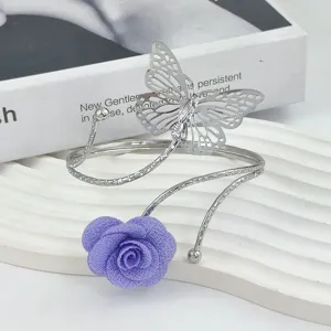 Detail view of silver metal arm cuff featuring hollow butterfly and purple fabric rose flower.