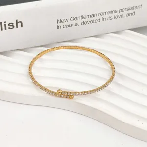 Primer plano de una pulsera de circonitas multicapa dorada con extremos de doble bola.