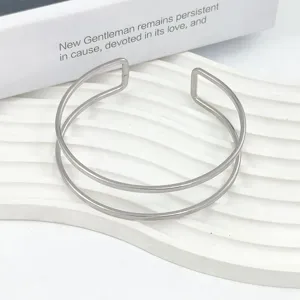 Vista di dettaglio ravvicinata del design minimalista del bracciale aperto in metallo.