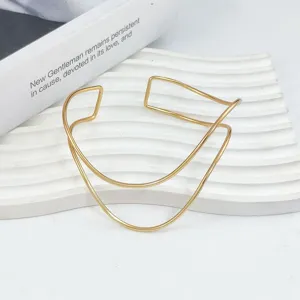 Bracciale rigido geometrico dorato minimalista, elegante gioiello da braccio in metallo.