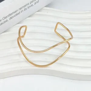 Vista dettagliata del bracciale aperto geometrico, design in metallo dorato minimalista ed elegante.