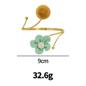 Gold open arm cuff bracelet featuring a textured metal ball and green fabric flower design.