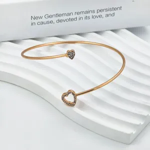 Detailopname van roségouden manchetarmband met sprankelende kristal bezette dubbele hartbedels.