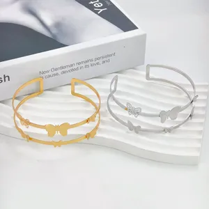 Elegante bracciale aperto in metallo con delicati motivi di farfalle traforate in oro e argento.